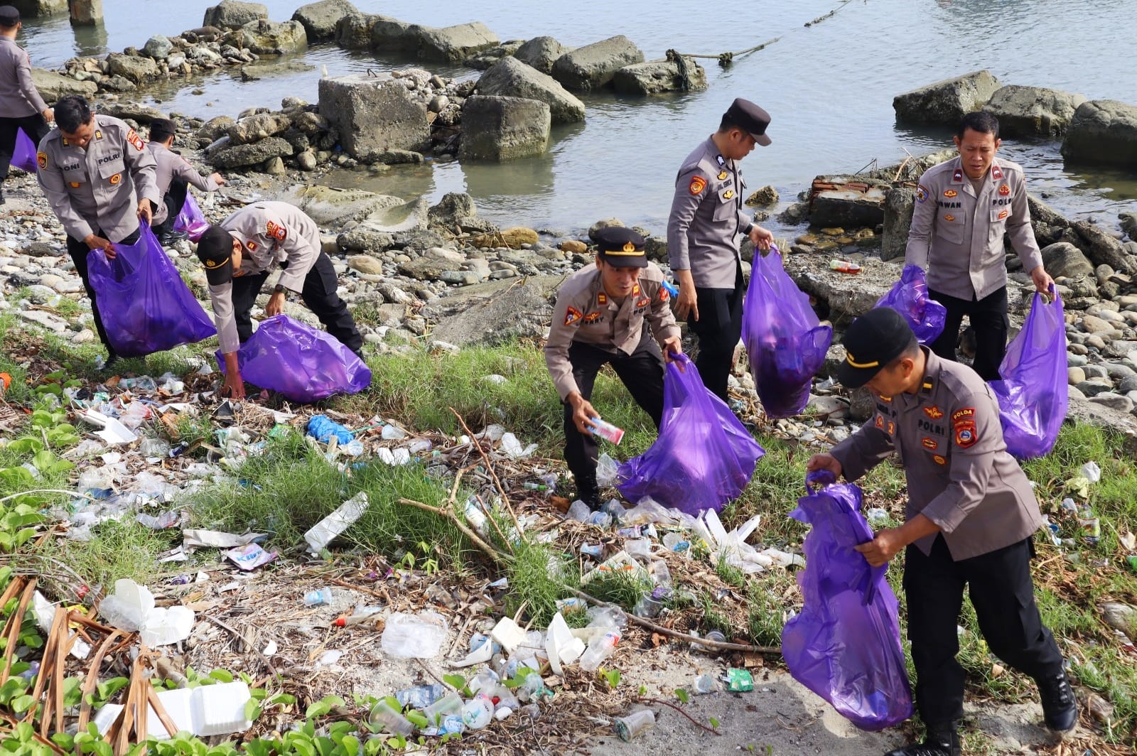 Tampak anggota Polres Poso mengumpulkan sampah yang tersebar disepanjang bibir pantai Kabose